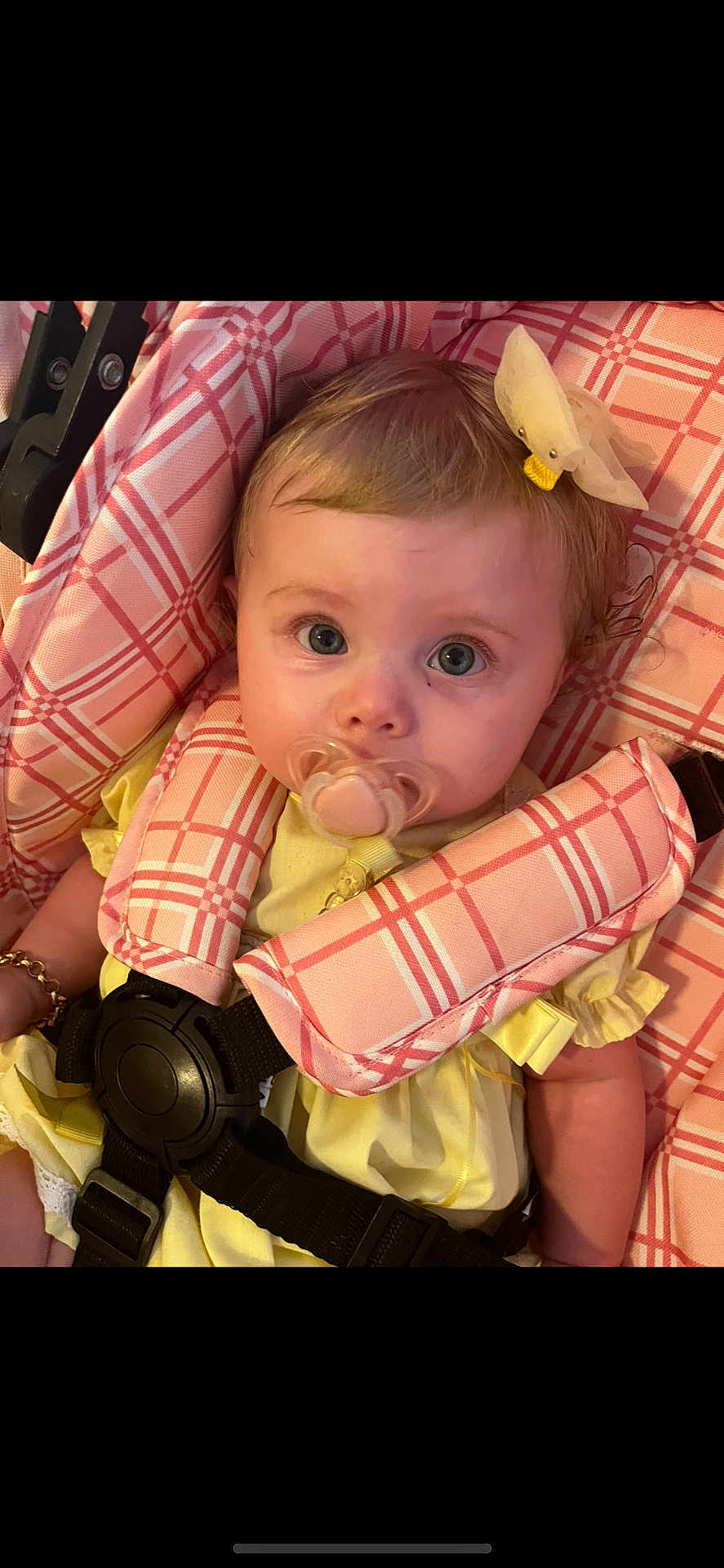Athena joined the competition — help win amazing prizes! baby, pacifier, car_seat, yellow_clothing, pink_plaid, bow, child, infant, face, blue_eyes, hair, cute, sitting, child_seat, safety_harness, portrait, indoor, person, closeup, adorable