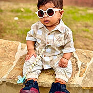 Adrian is registered to the contest to win money with this photo: toddler, child, sunglasses, shirt, pants, sneakers, stone, outdoor, grass, fashion, cute, baby, footwear, accessory, pacifier, casual, sitting, young_child, portrait, summer
