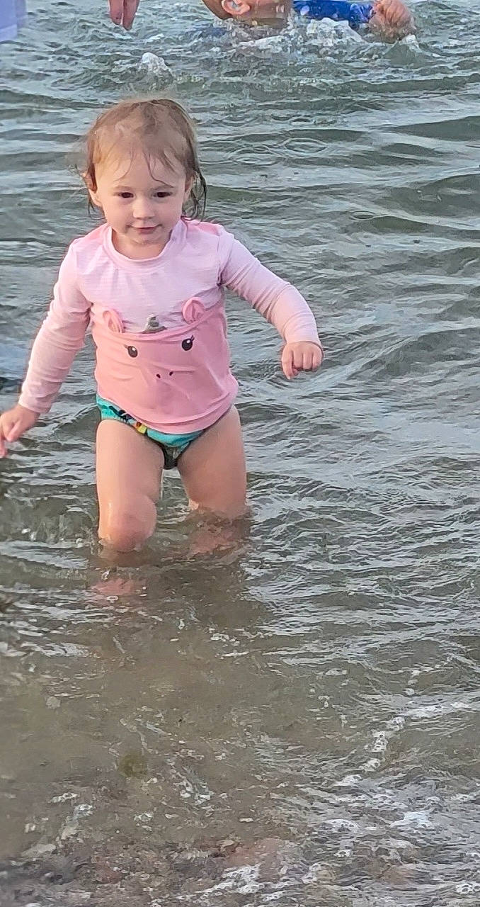 Lillyanna is registered to the contest to win money with this photo: barefoot, bathing, beach, fun, happy, head, human_leg, joy, lake, leg, leisure, people_in_nature, people_on_beach, person, personal_protective_equipment, recreation, smile, swimwear, thigh, toddler