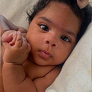 Ella joined the competition — help win amazing prizes! baby, infant, child, face, hair_bow, blanket, skin, cute, portrait, expression, hand, lying_down, indoors, newborn, soft_texture, chubby_cheeks, curious, young, close_up, sleepwear