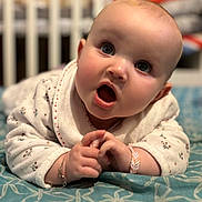 Leona participe au concours pour gagner de l'argent avec cette photo : baby, infant, face, hands, blanket, crib, expression, clothing, bracelet, pattern, blue, white, sleepwear, indoor, cute, child, portrait, closeup, soft, background