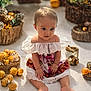 baby, child, dress, sitting, baskets, dried_flowers, indoor, curious, colorful_clothing, barefoot, decor, natural_light, floor, portrait, infant, cute, hands, feet, closeup, soft_light