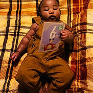 Azaan joined the competition — help win amazing prizes! baby, blanket, brown_clothing, child, close_up, colorful, corduroy, cozy, face, feet, hands, indoor, infant, lying_down, mickey_mouse, overalls, plaid, portrait, tablet, toy