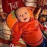 baby, child, infant, autumn, pumpkin, orange_outfit, smiling, happy, portrait, face, eyes, open_mouth, lying_down, cushion, blanket, pillows, fall_decor, pinecones, indoor, seasonal_decoration