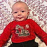 Mark is registered to the contest to win money with this photo: baby, infant, child, smiling, tongue_out, portrait, lying_down, red_shirt, black_pants, excavator, workwear, blanket, patterned_blanket, indoor, closeup, face, eyes, happy, cozy, photography