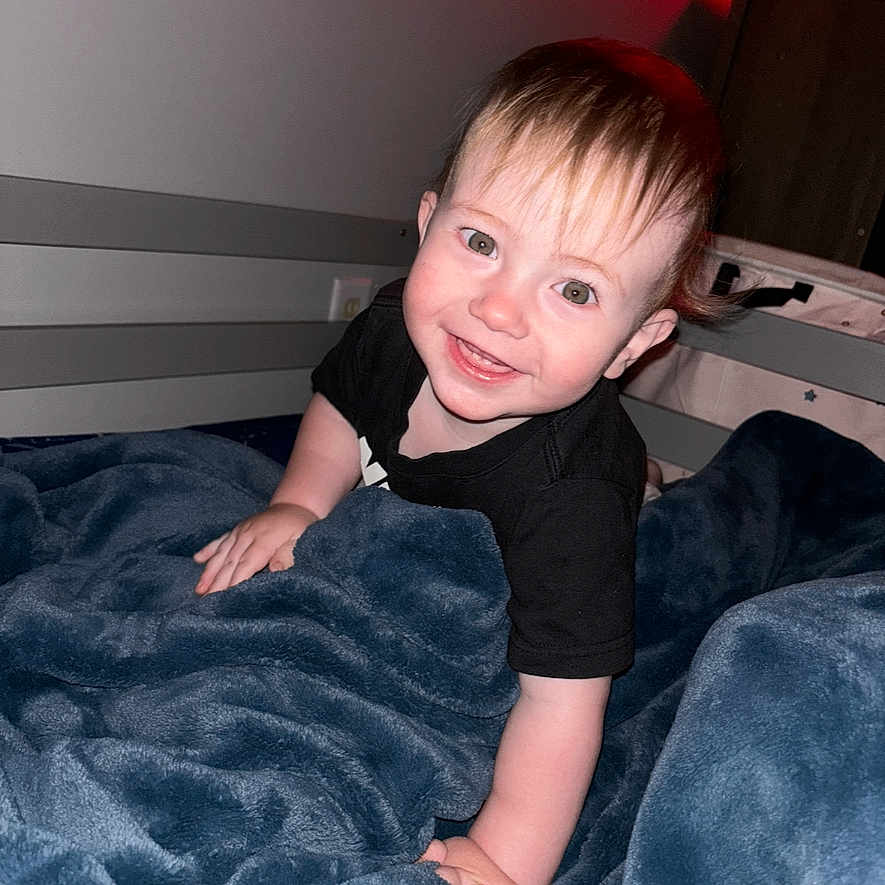 Wren joined the competition — help win amazing prizes! baby, bed, black_shirt, blanket, child, cozy, crawling, cute, face, furniture, hair, happy, home, indoor, lamp, person, portrait, red_light, smiling, toddler