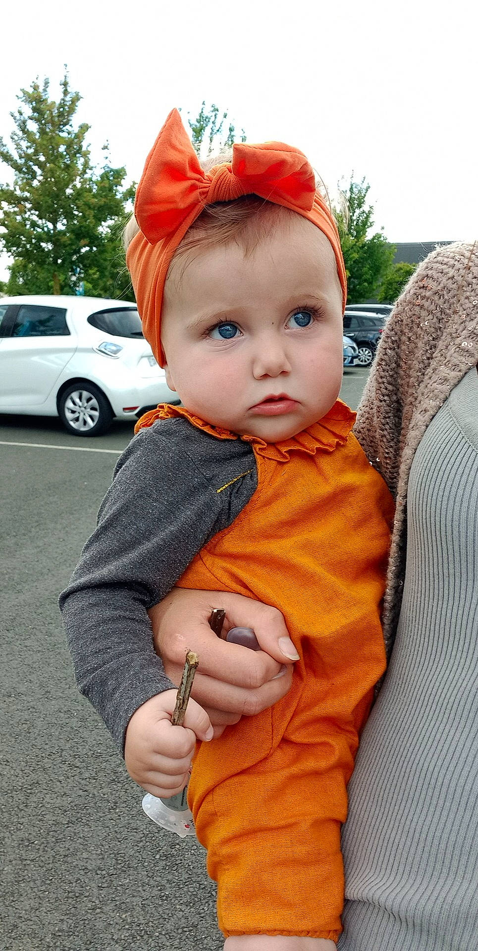 Ambre a rejoint le concours — aidez-le/la à gagner de superbes lots ! automotive_lighting, baby, baby_toddler_clothing, cap, car, chin, eye, face, hat, lip, orange, person, skin, sky, sleeve, standing, tire, toddler, tree, vehicle