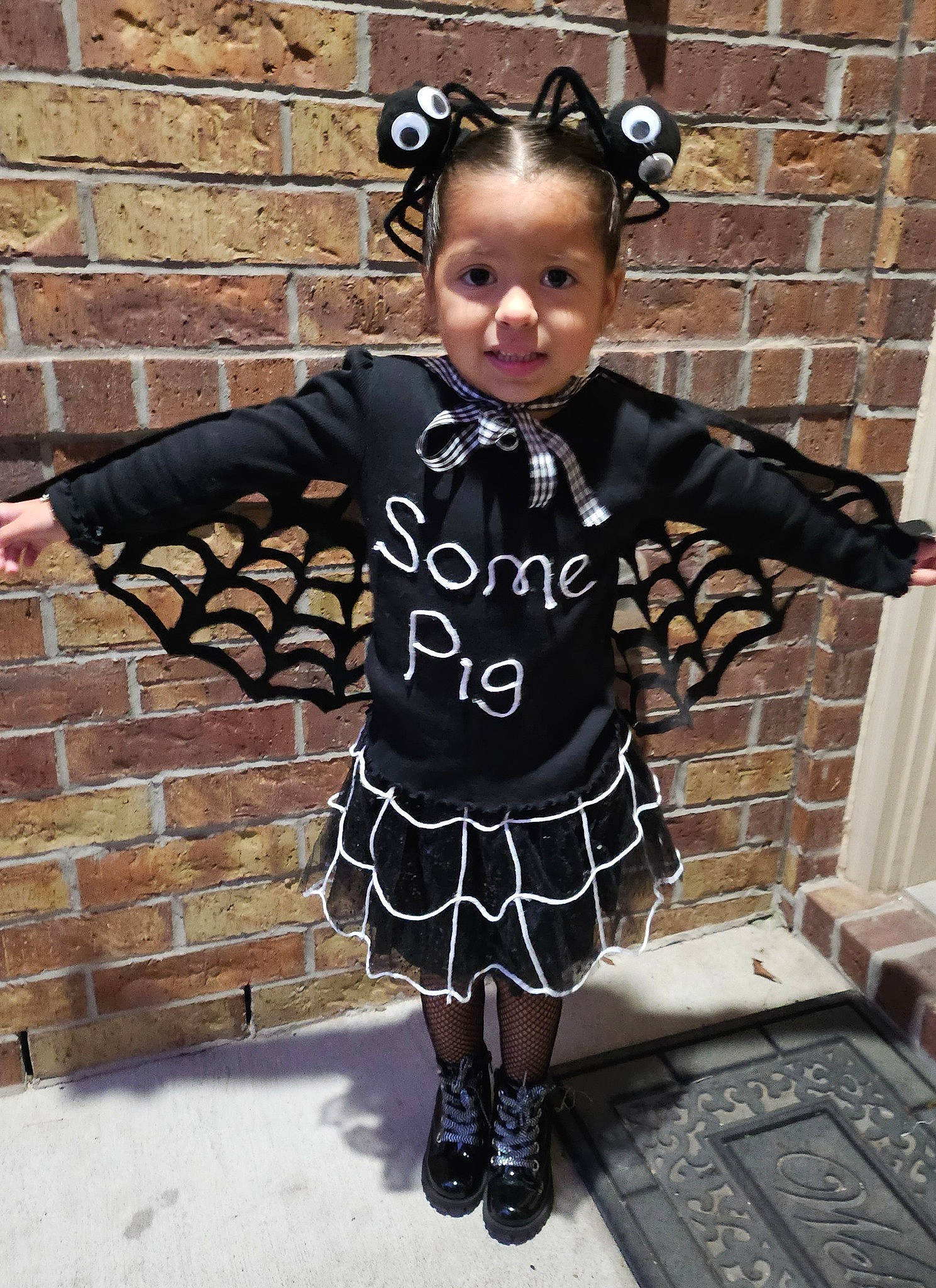 Camila joined the competition — help win amazing prizes! baby_toddler_clothing, brick, brickwork, child, cool, day_dress, dress, fashion_design, formal_wear, hairstyle, happy, outerwear, pattern, person, plaid, sleeve, standing, tartan, textile, toddler