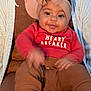 Malaina is registered to the contest to win money with this photo: baby, child, smile, headband, bow, drool, red_shirt, heart_breaker, pants, shoes, sitting, person, adult, cardigan, necklace, brown_clothing, indoor, closeup, happy, cute
