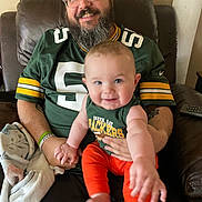 Jacen joined the competition — help win amazing prizes! man, baby, smile, green_bay_packers, jersey, glasses, beard, orange_pants, tank_top, leather_chair, blanket, indoor, happy, holding, family, portrait, casual, relaxed, person, home