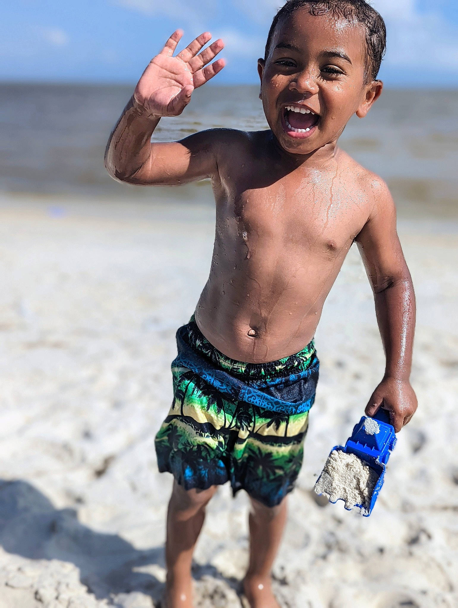 Tylan is registered to the contest to win money with this photo: barechested, beach, blue, board_short, chest, cloud, face, flash_photography, fun, gesture, hand, happy, people_in_nature, people_on_beach, person, sky, smile, toddler, trunk, trunks