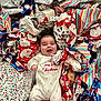 baby, infant, smiling, christmas, wrapping_paper, holiday, festive, onesie, happy, cute, indoors, celebration, gift, colorful, floor, red, white, blue, patterned, joyful