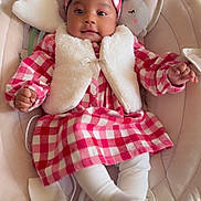 Soëlya a rejoint le concours — aidez-le/la à gagner de superbes lots ! baby, infant, child, dress, headband, plush_toy, baby_rocker, white_vest, checkered_pattern, cozy, smiling, cute, indoor, soft_fabric, toddler, sitting, clothing, comfort, portrait, happy