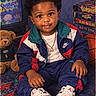 child, toddler, portrait, sitting, smiling, indoors, living_room, tracksuit, sneakers, gold_chain, teddy_bear, retro_tv, vhs_tapes, basketball, carpet, vintage, 1990s, fashion, close_up, date_stamp
