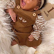 Zalayah Eaton is registered to the contest to win money with this photo: baby, infant, child, portrait, smiling, tongue_out, headband, flower, overalls, brown_clothing, striped_sleeves, socks, blanket, fluffy_blanket, lying_down, indoor, cozy, happy, close_up, photography