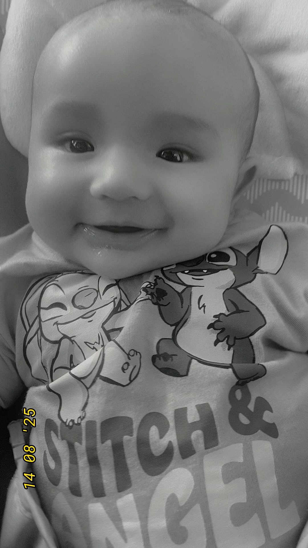 Codie is registered to the contest to win money with this photo: baby, smile, drool, shirt, cartoon, stitch, angel, closeup, black_and_white, child, face, happy, infant, clothing, text, toddler, cute, portrait, lying_down, soft