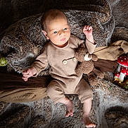 Jules a rejoint le concours — aidez-le/la à gagner de superbes lots ! baby, infant, teddy_bear, plush_toy, brown_clothing, fur_blanket, autumn_decor, pumpkins, gourds, pine_cones, mushrooms, cozy, soft_texture, cute, lying_down, indoors, warm_colors, decorative_lights, child, portrait