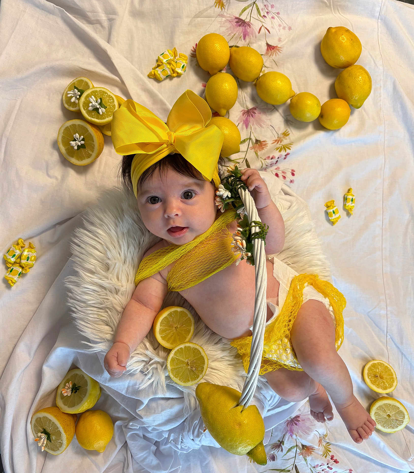 Baptistine participe au concours pour gagner de l'argent avec cette photo : baby, infant, yellow_bow, lemon, lemon_slice, white_cushion, yellow_clothing, diaper, flower_decoration, fabric_background, cute, portrait, smiling, indoors, soft_texture, child, fruit, colorful, playful, resting