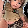 baby, child, person, blue_eyes, shorts, shirt, duck_patch, camo_pattern, lap, skin, hair, hand, curious, casual_clothing, indoor, close_up, portrait, relaxed, cute, infant