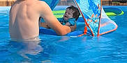 Asher is registered to the contest to win money with this photo: child, baby, boy, pool, water, float, sunshade, outdoor, summer, trees, nature, swimming, blue, happy, smiling, playing, vacation, fun, family, sunlight