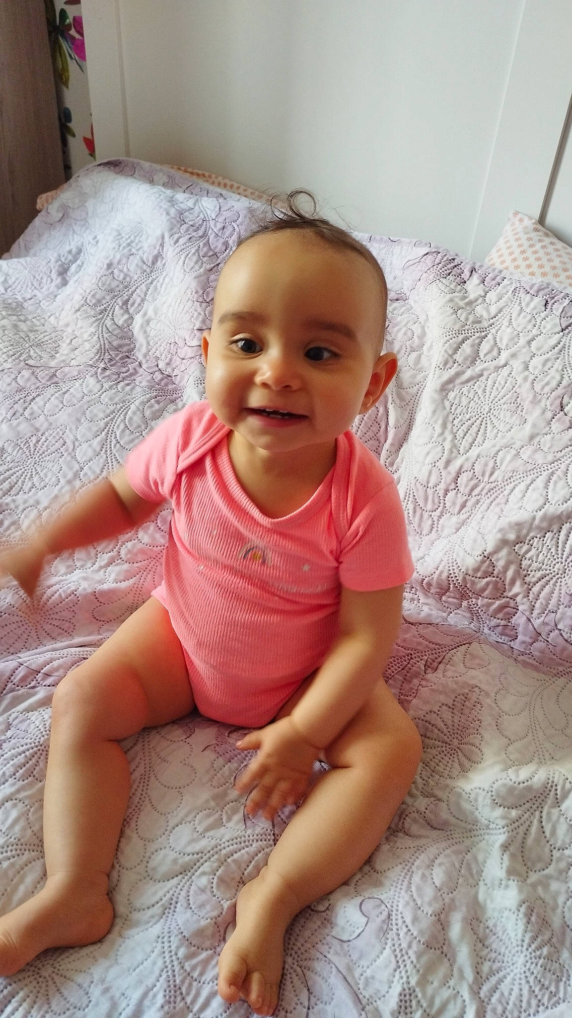 Naïma participe au concours pour gagner de l'argent avec cette photo : baby, baby_toddler_clothing, cheek, child, comfort, finger, floor, flooring, happy, human_leg, linens, pattern, person, pink, product, skin, sleeve, smile, textile, thumb