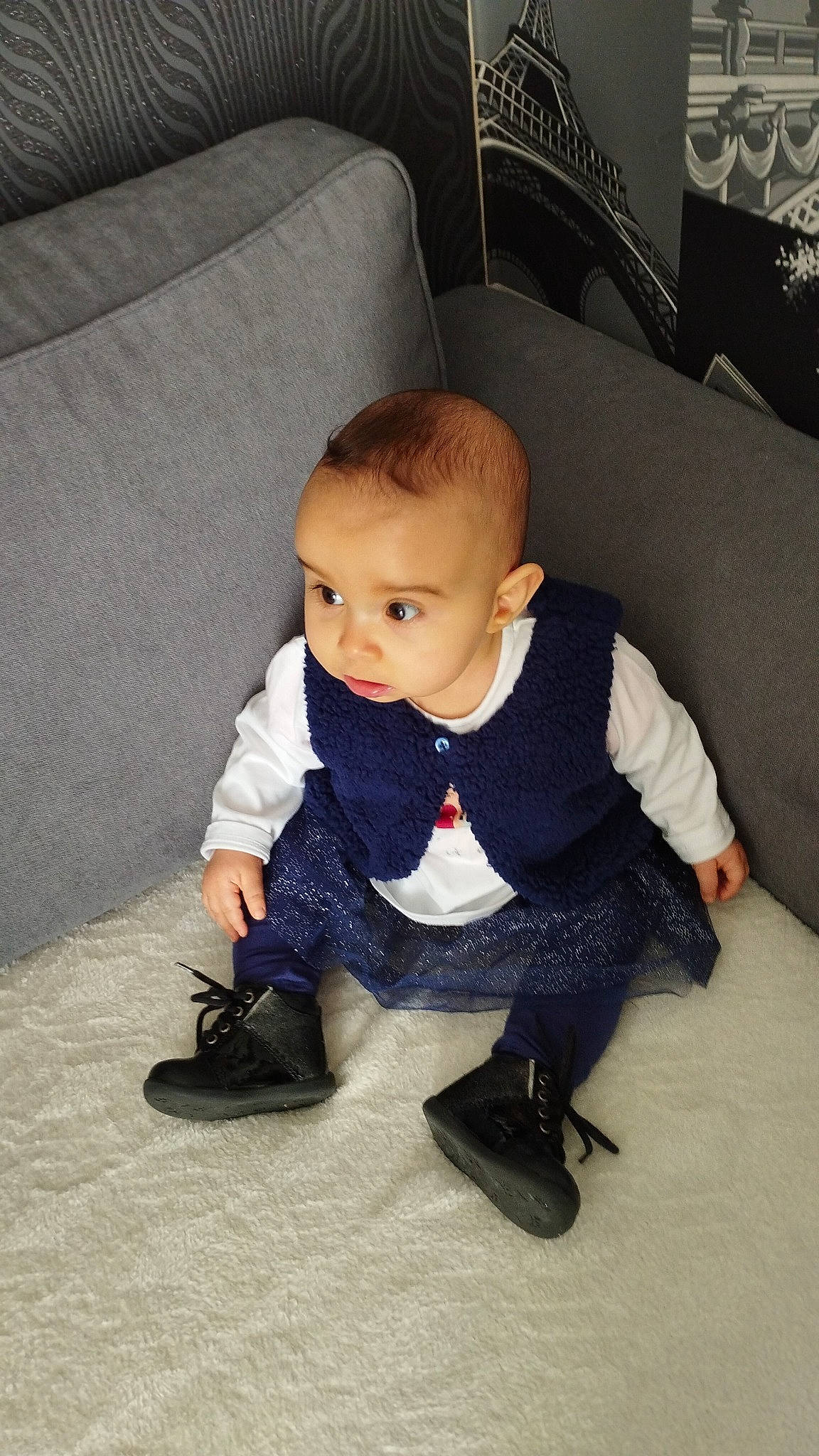 Naïma a rejoint le concours — aidez-le/la à gagner de superbes lots ! baby, baby_toddler_clothing, carpet, child, comfort, couch, dress, floor, flooring, foot, footwear, grey, human_leg, knee, person, sitting, sleeve, sneakers, t_shirt, toddler