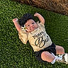 Rayleigh joined the competition — help win amazing prizes! baby, child, grass, smiling, outdoor, flower, headband, black_bow, shirt, text_on_clothing, shoes, leopard_print, happy, cute, infant, person, nature, summer, casual_clothing, lying_down