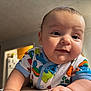 baby, infant, face, smile, onesie, colorful_clothing, cute, indoor, child, portrait, skin, head, arm, happy, young, person, baby_girl, baby_boy, expression, closeup