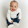 baby, blue_jeans, casual_clothing, child, cute, front_view, happy, indoors, infant, isolated, person, portrait, sitting, small_child, smiling, studio, white_background, white_shoes, white_sweater, young_child