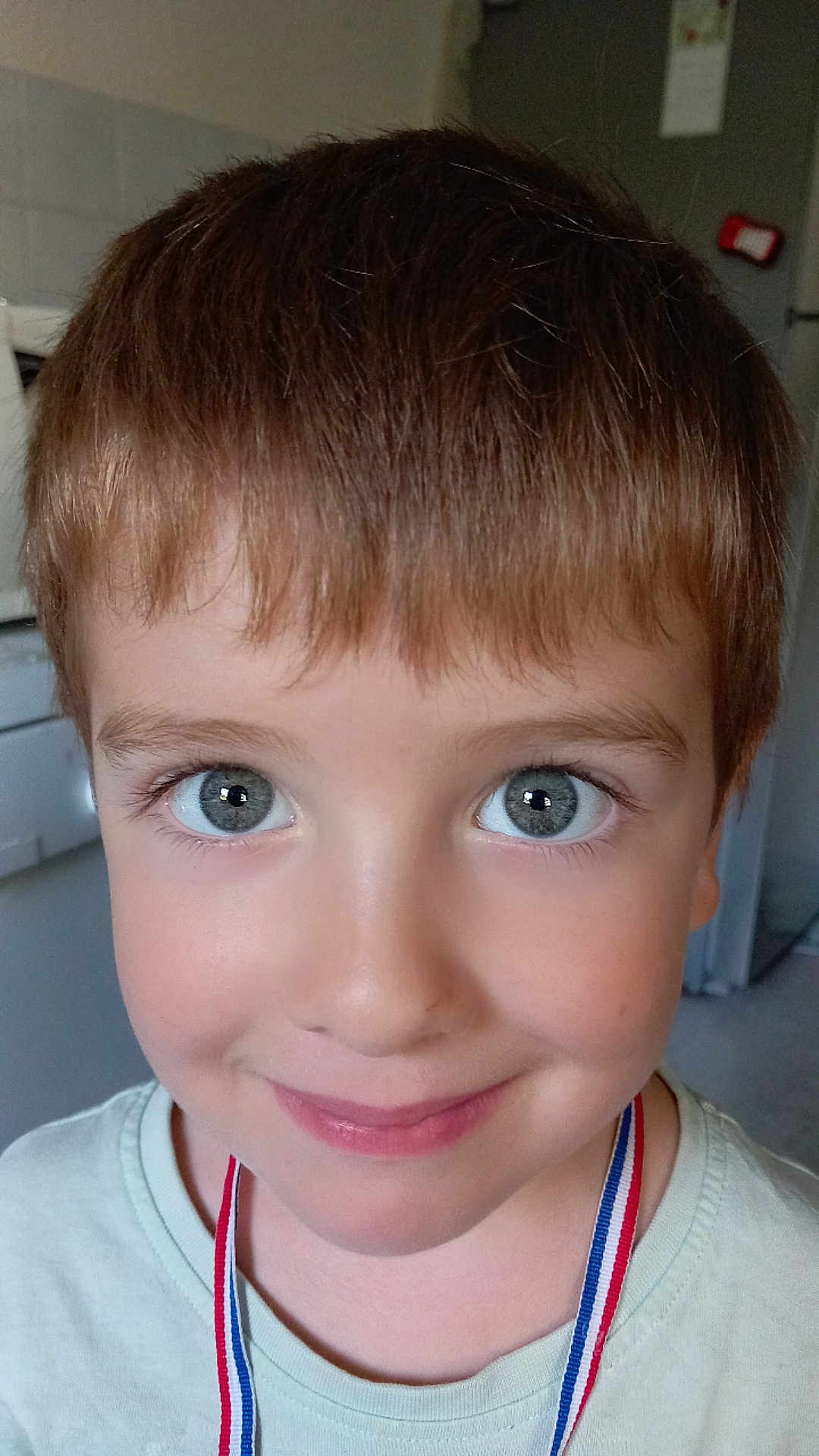 Adrien participe au concours pour gagner de l'argent avec cette photo : child, boy, face, smile, blue_eyes, hair, ribbon, necklace, indoor, portrait, closeup, happy, casual_clothing, young, cute, skin, person, head, expression, background