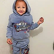 Lorenzo is registered to the contest to win money with this photo: child, toddler, smiling, hoodie, tracksuit, standing, portrait, indoors, wall, shadow, fashion, clothing, cartoon_car, race_car, red_treat, happy, boy, full_body, casual, photography