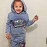 child, toddler, smiling, hoodie, tracksuit, standing, portrait, indoors, wall, shadow, fashion, clothing, cartoon_car, race_car, red_treat, happy, boy, full_body, casual, photography