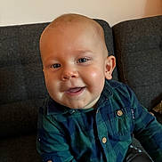 Noah participe au concours pour gagner de l'argent avec cette photo : baby, child, smile, face, plaid_shirt, blue_eyes, couch, indoor, person, happy, sitting, young_child, buttoned_shirt, casual_clothing, infant, cute, portrait, head, skin, cheerful
