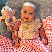 Penelope is registered to the contest to win money with this photo: baby, smiling, blanket, crochet, plush_toy, octopus_toy, baby_bib, pacifier, baby_clothing, baby_chair, elephant_pattern, indoor, child, happy, cute, portrait, infant, pink, beige, cozy