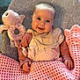 baby, smiling, blanket, crochet, plush_toy, octopus_toy, baby_bib, pacifier, baby_clothing, baby_chair, elephant_pattern, indoor, child, happy, cute, portrait, infant, pink, beige, cozy