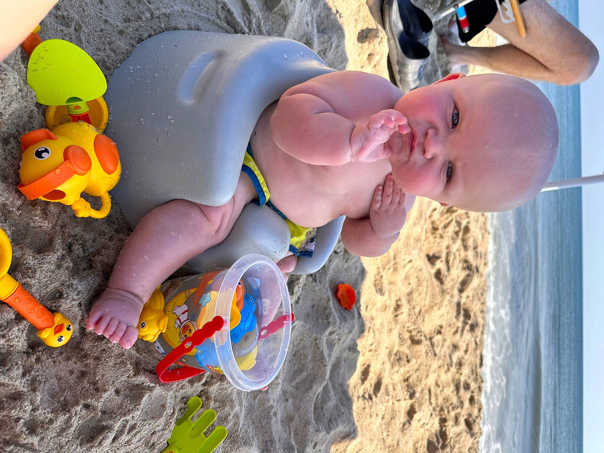 Henley is registered to the contest to win money with this photo: baby, beach, chest, child, eyewear, fun, happy, hat, leg, leisure, organ, people_on_beach, person, personal_protective_equipment, play, recreation, sand, swimwear, thigh, toddler