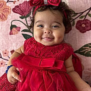Keziah joined the competition — help win amazing prizes! baby, child, smile, red_dress, bow, headband, dimples, tongue, floral_blanket, cute, portrait, infant, happy, indoors, person, lace, tulle, hand, face, soft