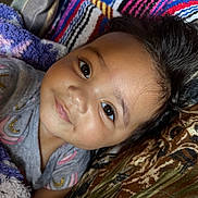 Elena is registered to the contest to win money with this photo: toddler, child, smiling, face, eyes, hair, blanket, colorful, patterned, fabric, portrait, closeup, happy, cute, skin, clothing, laying, indoors, person, baby