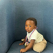 Théo a rejoint le concours — aidez-le/la à gagner de superbes lots ! award, baby, blue_chair, candid, casual_clothing, child, curious, cute, fuzzy_pants, indoor, looking_away, medal, person, plush, portrait, sitting, small_hands, soft_texture, toddler, young_child