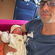 Mélodie a rejoint le concours — aidez-le/la à gagner de superbes lots ! newborn, baby, adult, man, glasses, sleeping, onesie, hat, indoor, chair, suitcase, desk, clothing, person, holding, cute, peaceful, portrait, family, home