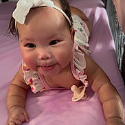 Ayani joined the competition — help win amazing prizes! baby, infant, headband, bow, tongue_out, pacifier, crib, purple_sheet, lying_down, cute, playful, chubby_cheeks, toy, soft_lighting, indoors, child, smiling, person, toddler, clothing