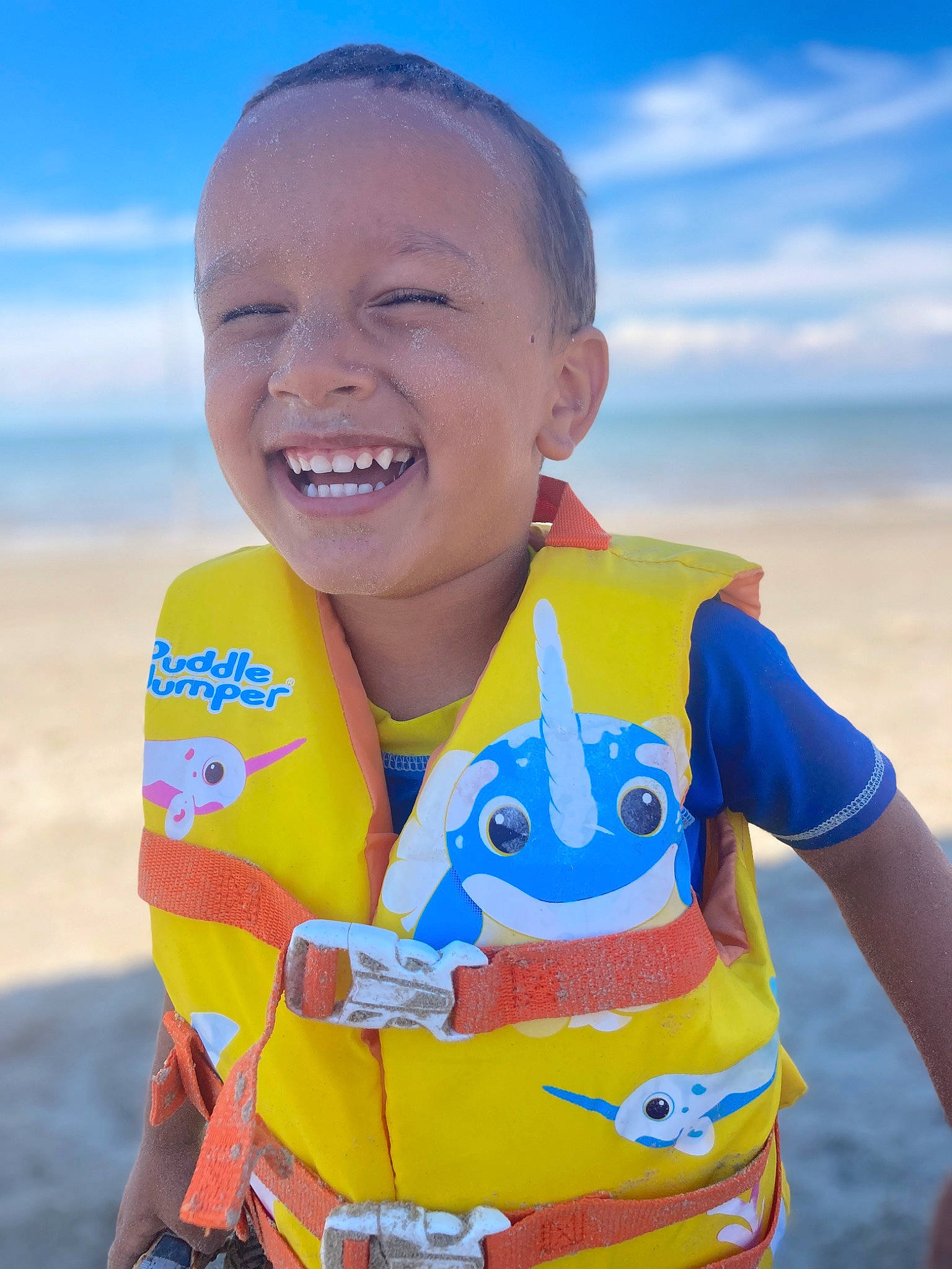 Jonah is registered to the contest to win money with this photo: beach, cloud, electric_blue, fun, gesture, happy, joy, landscape, leisure, natural_environment, people_in_nature, person, personal_protective_equipment, recreation, sand, sky, sleeve, smile, t_shirt, toddler
