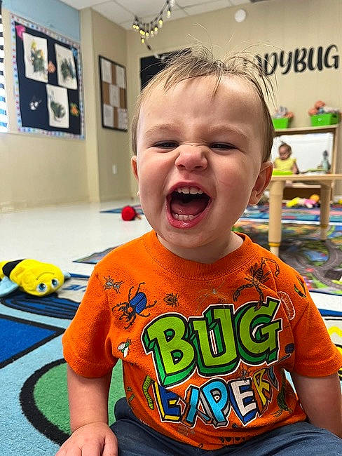 Benjamin is registered to the contest to win money with this photo: baby, baby_toddler_clothing, blurred, cheek, child, chin, facial_expression, fun, green, happy, mouth, nose, orange, person, picture_frame, room, sleeve, smile, t_shirt, toddler
