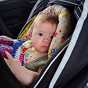 Octavia is registered to the contest to win money with this photo: baby, blanket, blue_eyes, candid, car_seat, child, clothing, comfort, crocheted, cute, face, floral_pattern, head_support, indoor, infant, person, portrait, seat_belt, soft_toys, vehicle