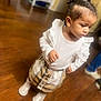 Zylah Brown joined the competition — help win amazing prizes! toddler, child, girl, white_top, plaid_skirt, standing, indoor, wooden_floor, portrait, young_child, long_sleeve, ponytail, footwear, blurred_background, warm_lighting, thinking, fashion, casual, cute, person