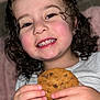 Naïla a rejoint le concours — aidez-le/la à gagner de superbes lots ! candid, child, closeup, cookie, cozy, curly_hair, cute, face, food, hands, happy, indoor, person, portrait, rosy_cheeks, smiling, snack, toddler, white_shirt, young_child