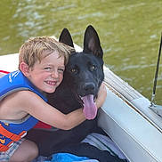 Cairo is registered to the contest to win money with this photo: child, dog, black_dog, boy, life_jacket, boat, water, hug, smile, tongue_out, pet, summer, outdoor, friendship, happy, towel, animal, cute, portrait, vacation