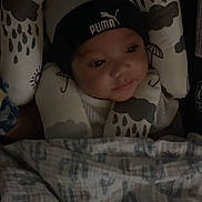 Silas joined the competition — help win amazing prizes! baby, infant, hat, puma, cushion, blanket, pattern, face, headwear, child, indoors, resting, soft, comfort, closeup, young, portrait, sleepwear, expression, cozy