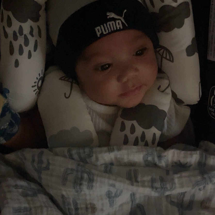 Silas joined the competition — help win amazing prizes! baby, infant, hat, puma, cushion, blanket, pattern, face, headwear, child, indoors, resting, soft, comfort, closeup, young, portrait, sleepwear, expression, cozy