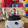 Myles joined the competition — help win amazing prizes! toddler, child, toy_car, birthday_party, presents, balloons, banner, indoor, floor, car, white_car, celebration, gift_wrapping, decorations, party, person, young_child, happy_birthday, wood_floor, ribbon